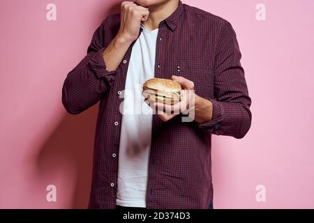 hungry man with hamburgers in hands fast food diet food emotions pink background Stock Photo