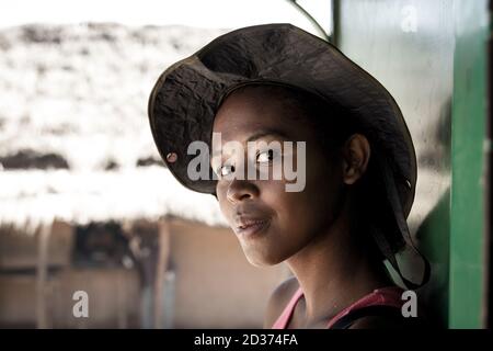 Beautiful woman with a hat looking at me with her big black deep eyes on the train from Fianarantsoa to Manakara, Madagascar Stock Photo