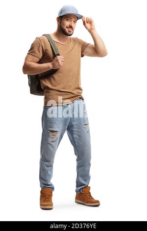 Full length portrait of a young man with a backpack and ripped jeans holding his cap isolated on white background Stock Photo