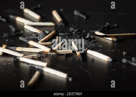 Used wooden matches with the remains of ashes on a black board. Selective focus. Hight contrast. Stock Photo