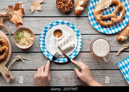 Celebrating Oktoberfest alone. Traditional food and beer, fat lay on wooden table with decorations. Stock Photo