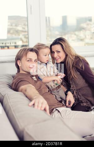 Happy family sitting on floor with their little baby. Family spending time at home with their son. Stock Photo