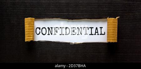 The word 'confidential' appearing behind torn black paper. Business concept. Stock Photo