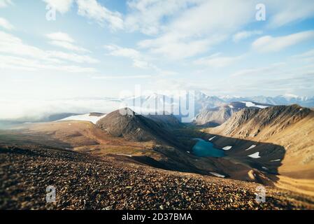 Beautiful atmospheric alpine landscape with snowy mountains, glaciers and mountain lake. Big snowy mountains with glacier and glacial lake. Thick low Stock Photo