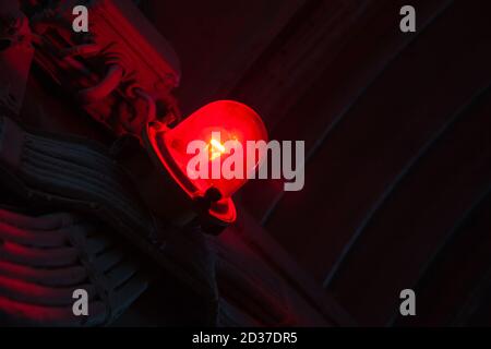 Red industrial caution light mounted on a metal wall glowing in dark, close-up photo with selective focus Stock Photo