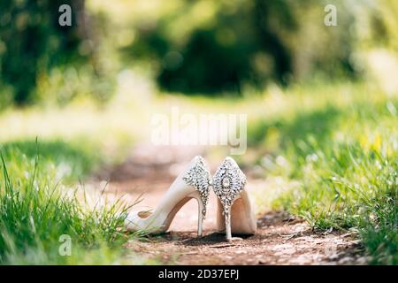 White shoes with a backdrop decorated with stones on a background of green grass with a shallow depth of field. Stock Photo