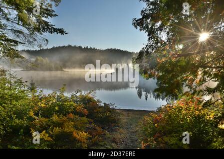 Early morning views of Lakes in Northern Ontario, Canada in the autumn. Fall colours and mist reflect on the lake. Stock Photo