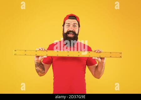 Perfect size. Bearded man with big measuring instrument. Measuring with ruler. Size measurement. Measuring length. Size clothes. Student study stem disciplines. Ruler tool equipment. Shop assistant. Stock Photo