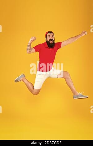 Healthy guy feeling good. Inspired concept. Towards fun. Enjoying active lifestyle. Happy guy jumping. Active bearded man in motion yellow background. Active and energetic hipster. Energy charge. Stock Photo