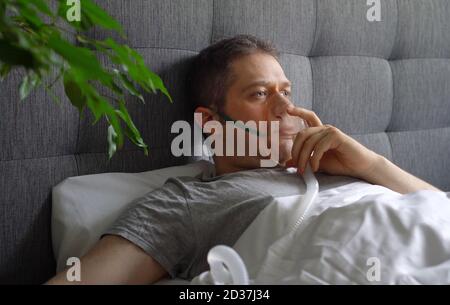 Sick man with inhalator mask on the face in bed. Coronavirus prevention concept. Stock Photo