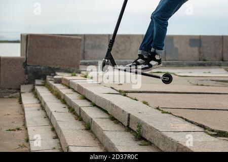 Boy on scooter makes a trick and enjoying his riding by skate in the city street. Stock Photo
