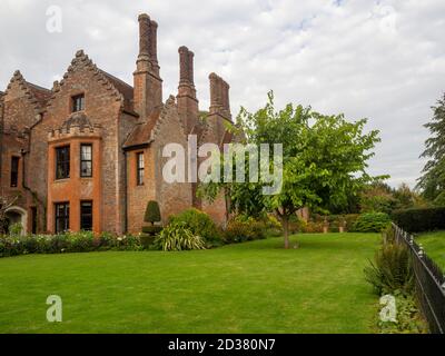 Chenies Manor gardens in September. South facing plant border with Mulberry tree and Parterre with wroght iron fence in perspective. Stock Photo