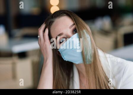 Female manager in suit and medical mask works remotely on street cafe. Stock Photo