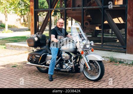 a biker posing smiling on his custom motorcycle Stock Photo