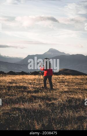Photographer taking photos in the mountains with mountains behind Stock Photo