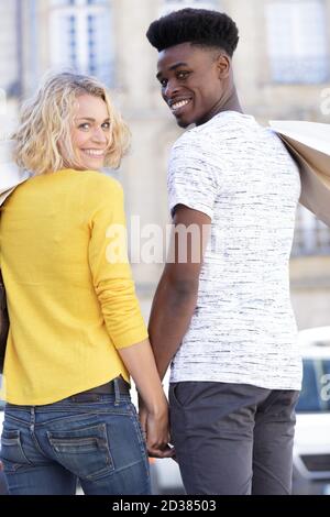 back view of interracial going couple shopping Stock Photo