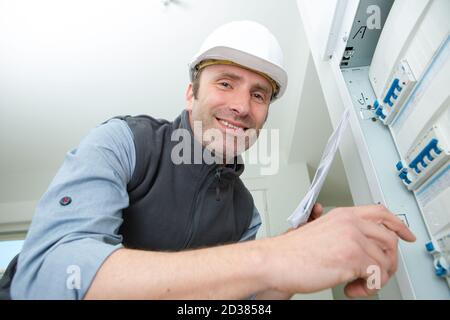 electrician posing and smiling next to a panel Stock Photo