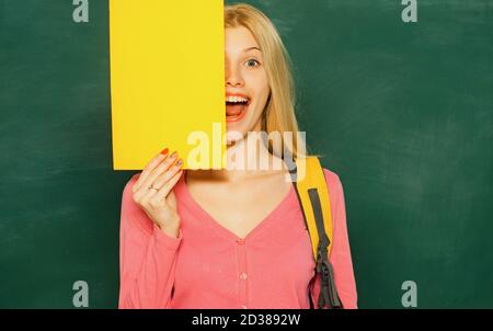 Happy girl holding announcement while stand in classroom. Student with backpack. High school education. Great opportunity. Looking for volunteers Stock Photo