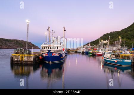 St. John's, Newfoundland/Canada-October 2020: Multiple sized bright and colorful fishing boats at a wooden wharf with the pink evening sky.