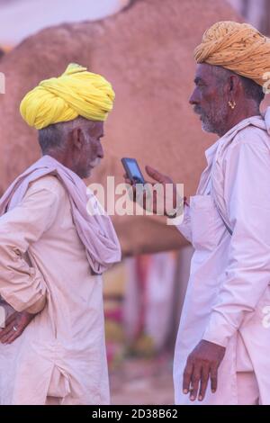 Two men wearing colorful turbans talking to each other at Pushkar, Rajasthan, India on 18 November 2018 Stock Photo