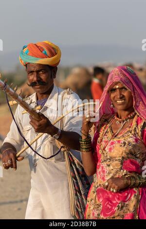 Man and a women wearing rajasthani clothes playing musical instrument violin at Pushkar festival at Pushkar, Rajasthan, India on 19 November 2018 Stock Photo