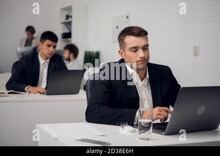 Two managers of a carsharing company are engaged in routine business in the office in a laptop. They are distracted from their work. Stock Photo