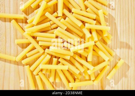Pile of yellow pasta maccheroni on wooden table  , dry pasta shaped like narrow tubes , Stock Photo