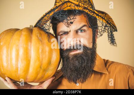 Portrait of Handsome man with pumpkin over isolated background. Devil man. Young man with witch hat ready to Halloween party. Halloween beaded man Stock Photo