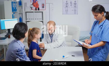 Doctor checking evolution of flu using stethoscope. Healthcare practitioner physician specialist in medicine providing health care services radiographic treatment examination in hospital cabinet Stock Photo