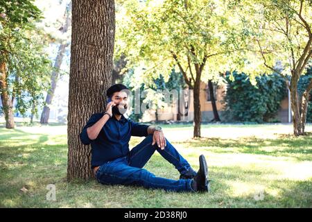 Young Indian man talking by phone in the park. Stock Photo