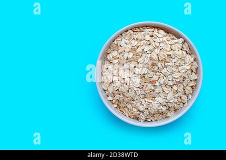Oat flakes in bowl on blue background. Healthy food concept Stock Photo