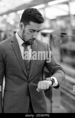 Young handsome Caucasian businessman looking watch at train station in Bangkok Thailand Stock Photo
