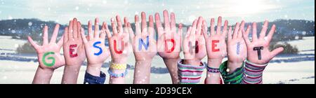 Kids Hands Holding Word Gesundheit Means Health, Snowy Winter Background Stock Photo