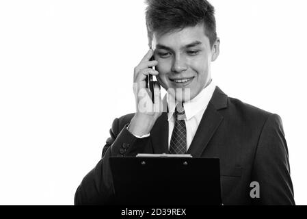 Close up of young happy businessman smiling while talking on mobile phone and reading on clipboard Stock Photo