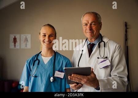 Portrait of Female and Male Doctors in scrubs and lab coat with digital tablet Stock Photo