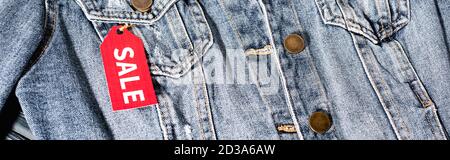 close up of red sale tag on blue denim jacket, panoramic crop Stock Photo