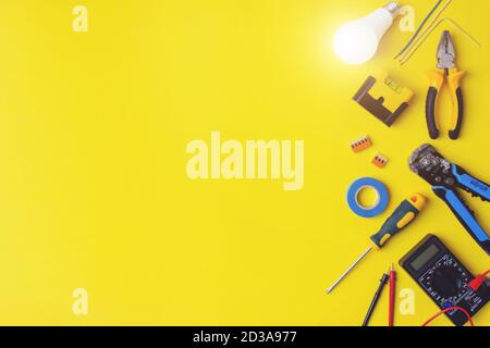 Set of electrician's tools on yellow background. Flat lay composition with electrician's tools and space for text yellow background. Work tools. Stock Photo