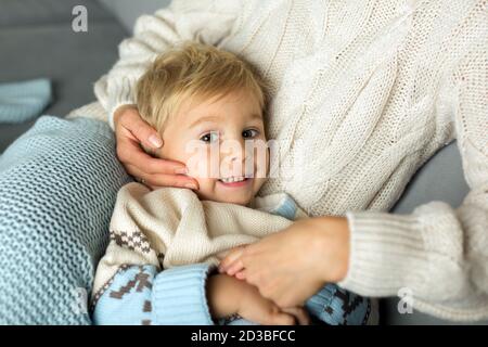 Mother and child, blond boy, lying on the couch at home, hugging Stock Photo