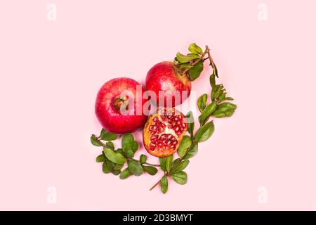A pomegranates with branches and leaves on a pink background and with copy space in a top view Stock Photo
