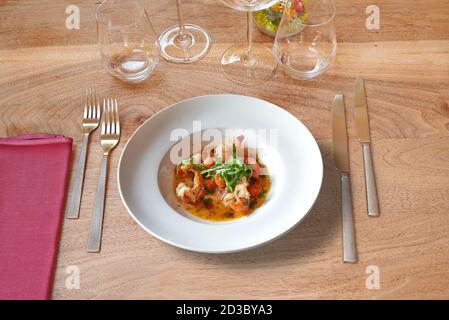Set of silverware on Brown wooden table with white round plate and garlic shrimps. Stock Photo