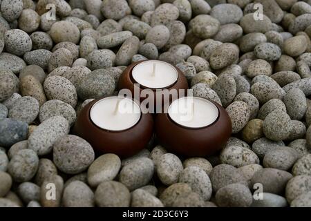 Birds eye view of 3 tealight candles isolated on a background of mottled stone pebbles Stock Photo
