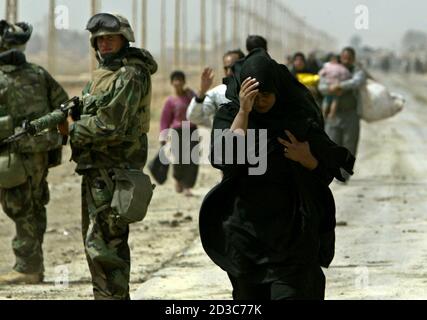 An Iraqi woman, a refugee from Baghdad, walks next to a U.S. Marine from Lima Company, a part of the 7th Marine Regiment, on the road south-east of the Iraqi capital April 5, 2003. U.S. Marine commander said on Saturday American troops would use overwhelming force to crush any resistance if ordered to storm Baghdad and that the battle would cost many civilian lives.