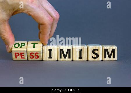 Male hand turns cubes and changes the expression 'pessimism' to 'optimism'. Beautiful grey background. Business concept. Copy space. Stock Photo