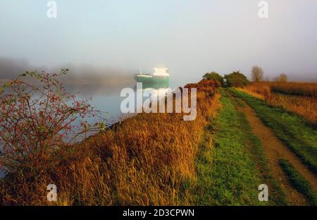 The ship - Polaris VG - appeared out of nowhere. It drove on the River Trave in fog. Stock Photo