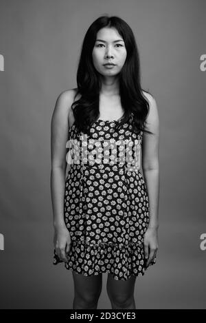 Asian woman wearing dress against gray background Stock Photo