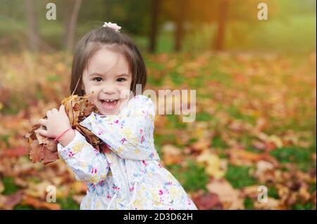 Portrait of happy playing in autumn park kid on blurred background Stock Photo