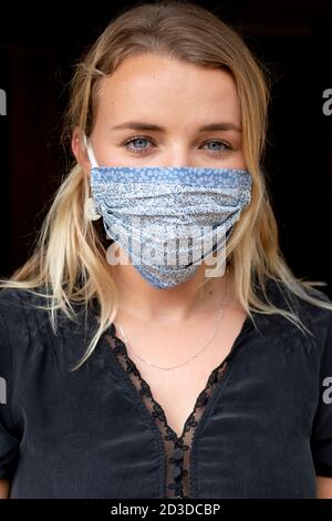 Portrait of young blond woman wearing blue face mask. Stock Photo