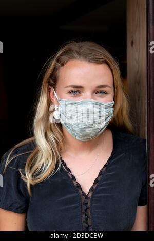 Portrait of young blond woman wearing blue face mask. Stock Photo