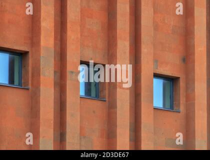 Texture of terracotta brick wall with parallel pattern and windows. Stock Photo