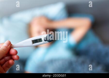 Sick teenage little girl with high fever and headache laying in bed. Stay at home during corona virus epidemic if you feel sick Stock Photo